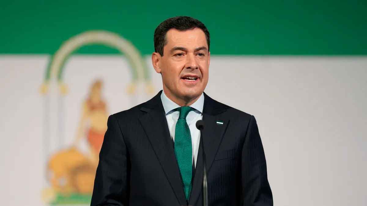 Presidente de la Junta de Andalucía en un podio con la bandera regional de fondo
