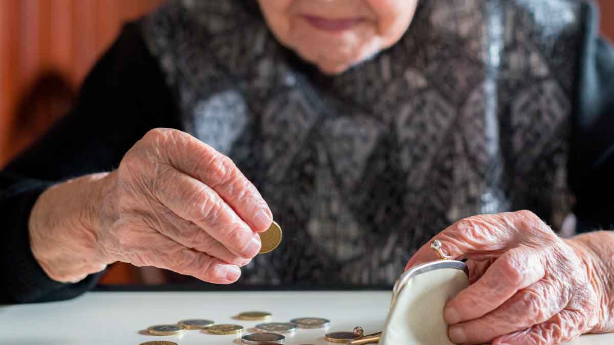 Manos de una persona mayor contando monedas para ilustrar la pensión no contributiva de 7.905 € de la Seguridad Social