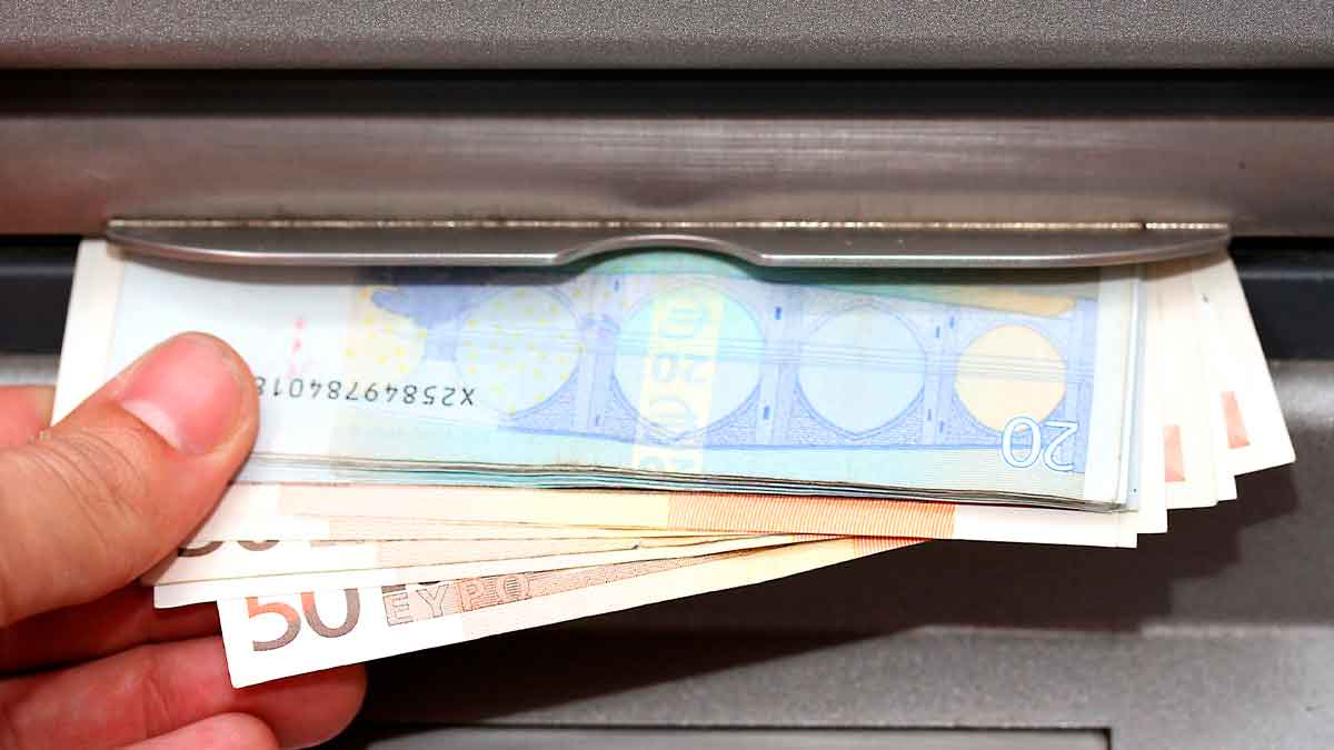 Billetes de euro saliendo de cajero automático por adelanto del pago de pensiones julio 2025