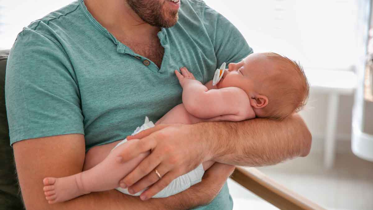 Padre sostiene a su bebé recién nacido, símbolo del permiso por nacimiento ampliado a 17 semanas y mejora del parental