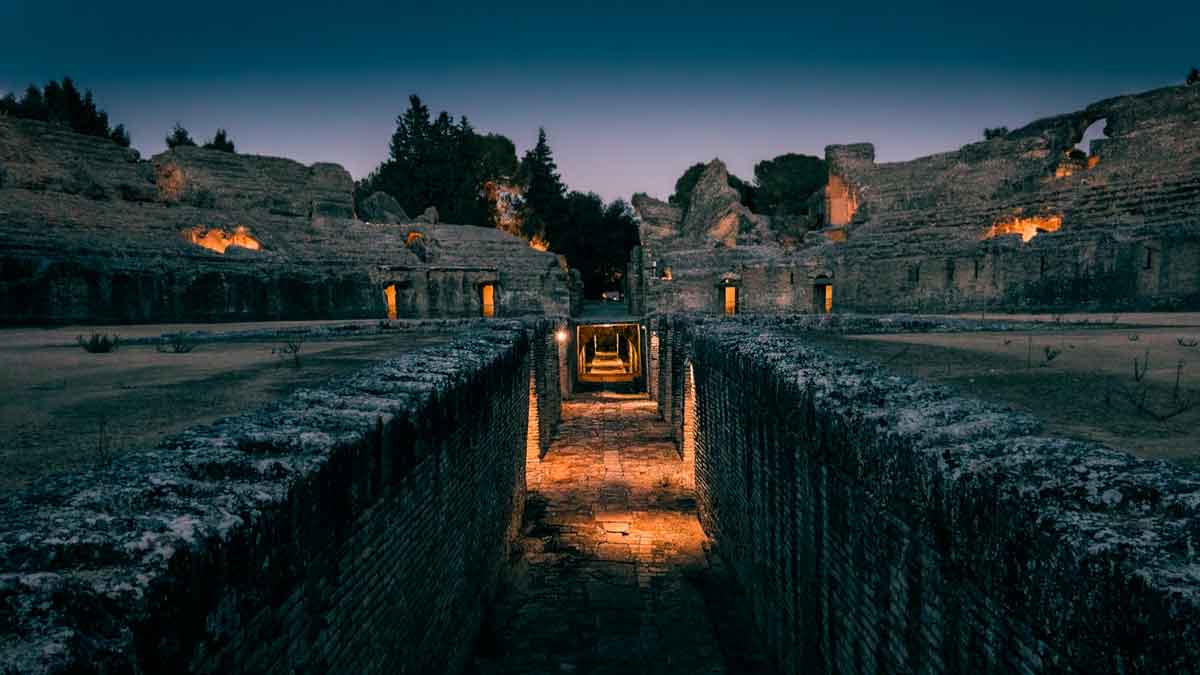 Visitas nocturnas al anfiteatro de Itálica en Sevilla iluminado durante el recorrido mágico de los sueños de Adriano