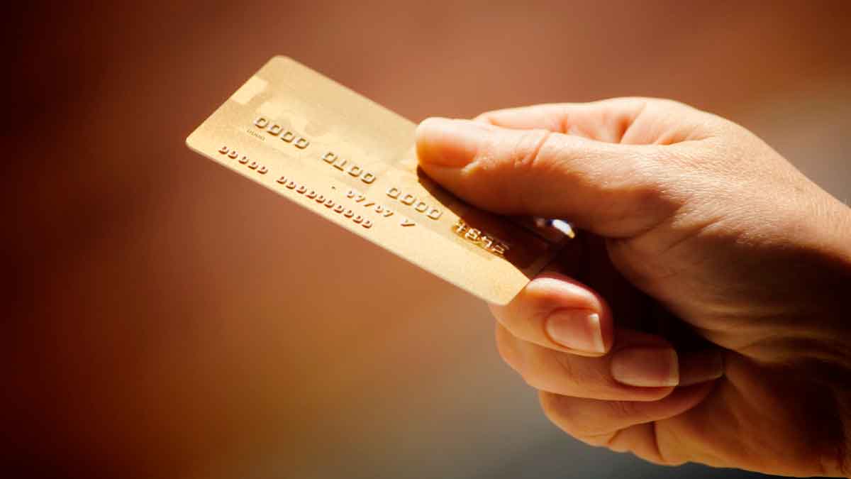 Mano sosteniendo una tarjeta de crédito dorada representando tarjetas revolving y consejos para pagar menos intereses