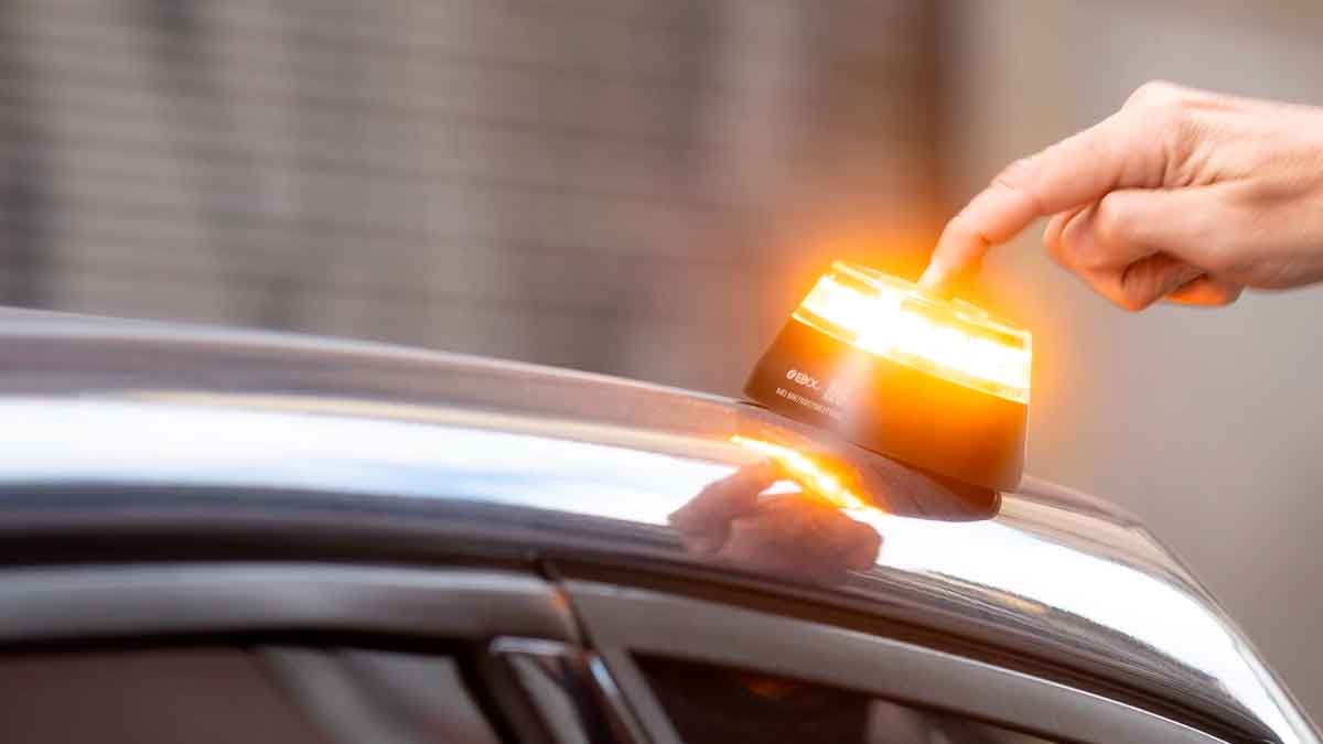 Conductor colocando una baliza v16 encendida en el techo del coche