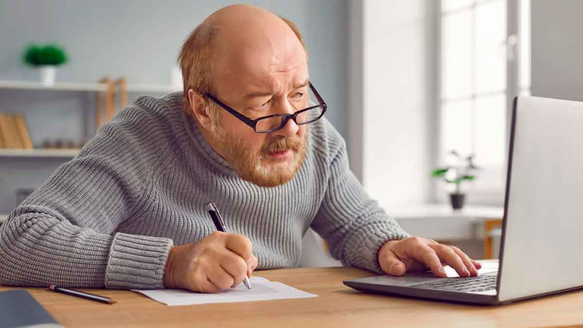 Hombre mayor calculando su pensión de jubilación en 2026 con un ordenador y documentos