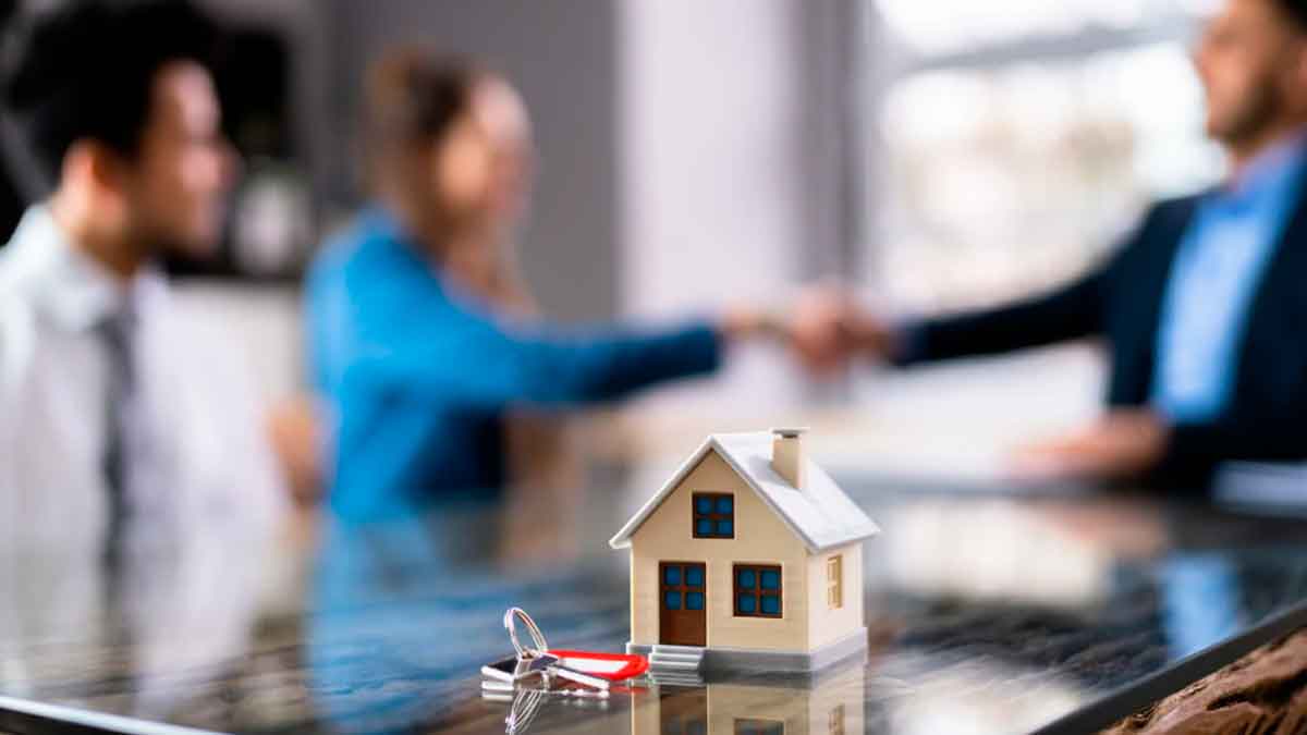 Personas cerrando una hipoteca en un banco con una casa y llaves sobre la mesa