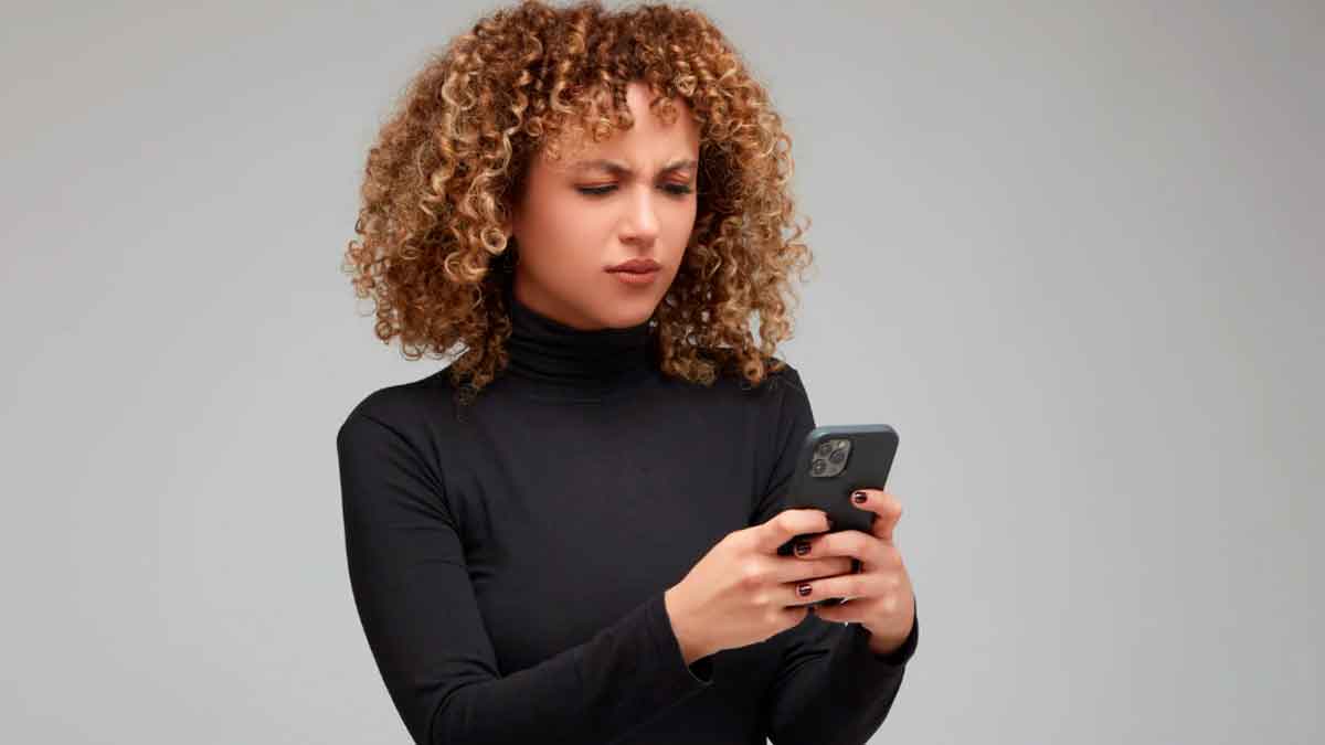 Mujer revisando su móvil con gesto de preocupación por posible espionaje o problemas de privacidad
