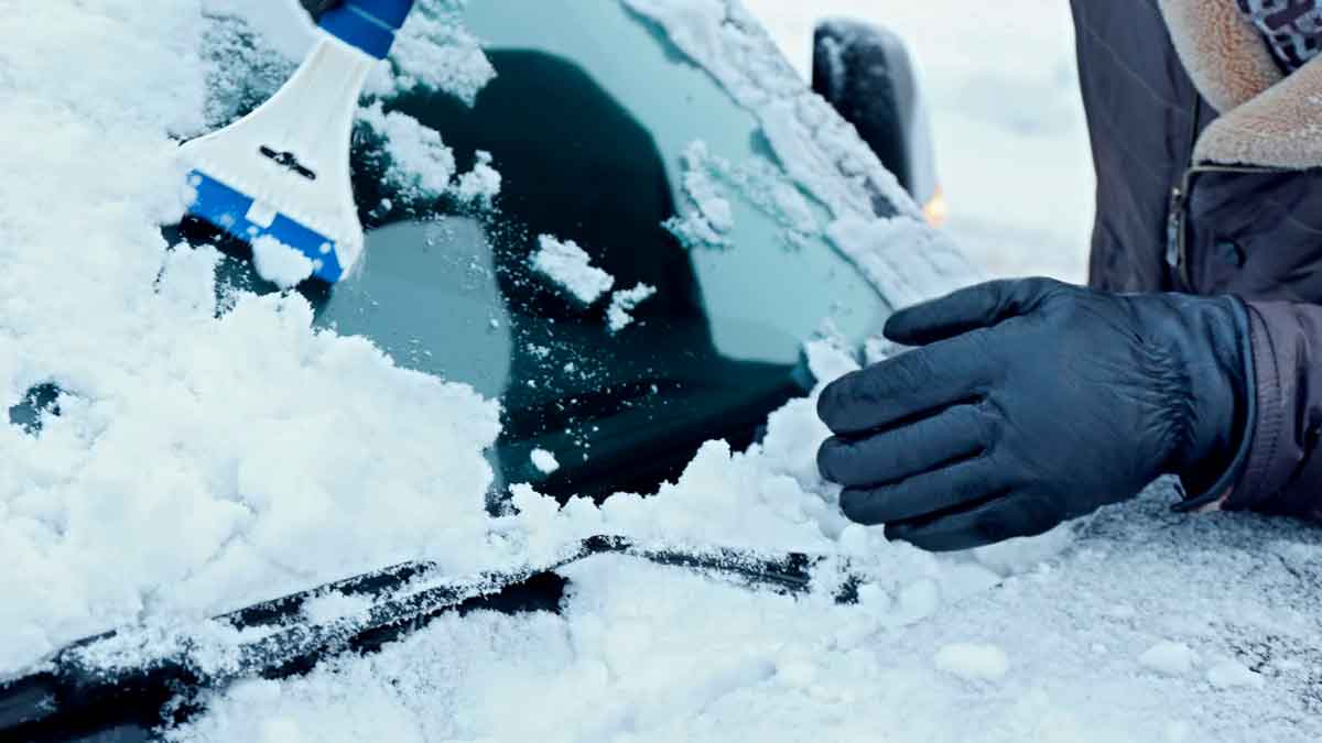 Rascar el parabrisas del coche con un rascador de plástico en un día de frío extremo
