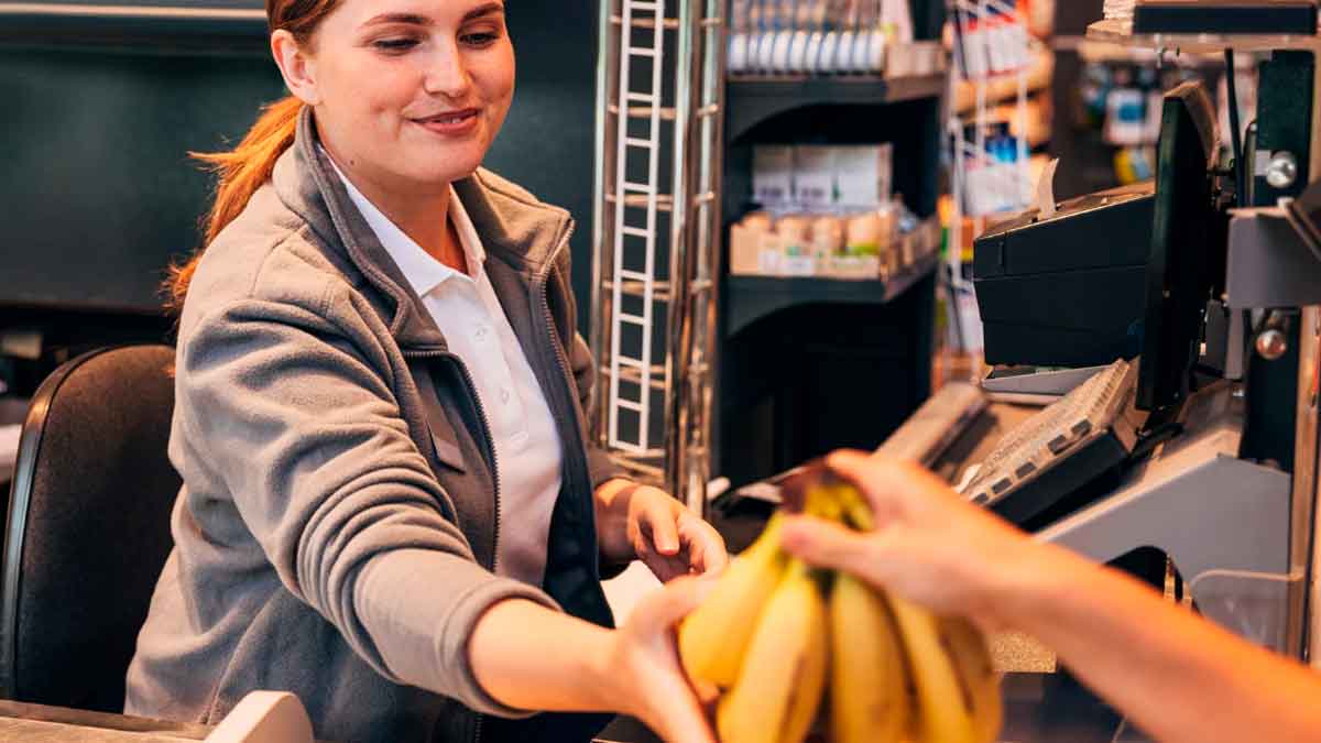 Cajera de supermercado cobrando productos en caja durante su jornada laboral