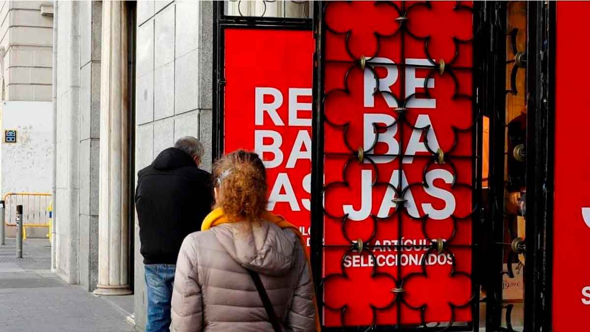Clientes entrando a una tienda durante las rebajas de enero con carteles rojos anunciando descuentos
