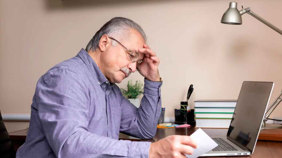 Hombre mayor revisando documentos laborales junto a un ordenador antes de acceder a la jubilación parcial en 2026