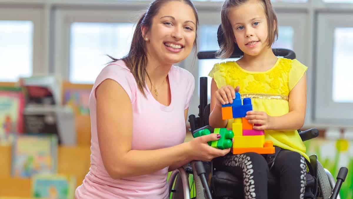 Madre junto a su hija con discapacidad jugando en una silla de ruedas en un entorno educativo
