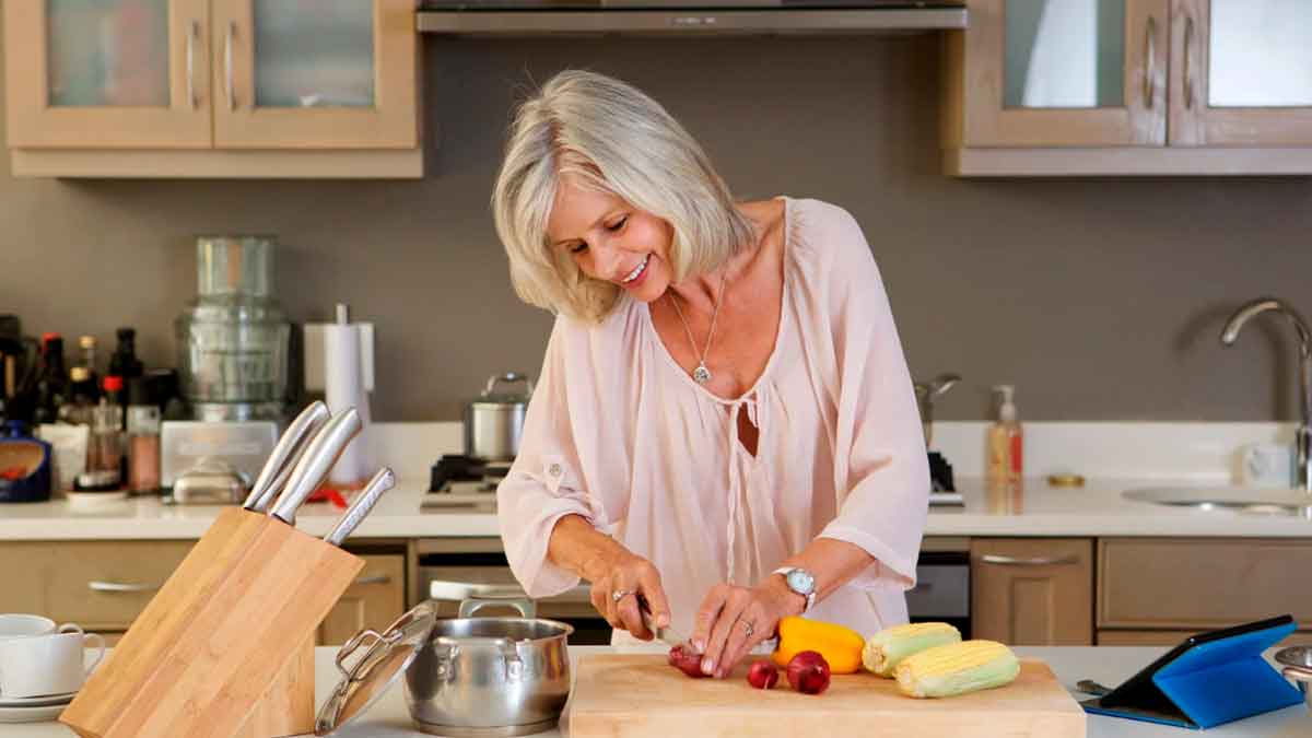 Mujer mayor de 50 años preparando comida saludable en su cocina