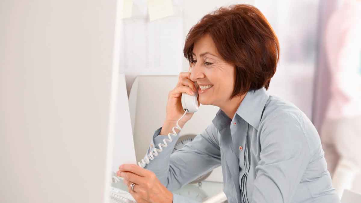 Trabajadora utilizando el teléfono fijo de la oficina para realizar una llamada personal durante su jornada laboral