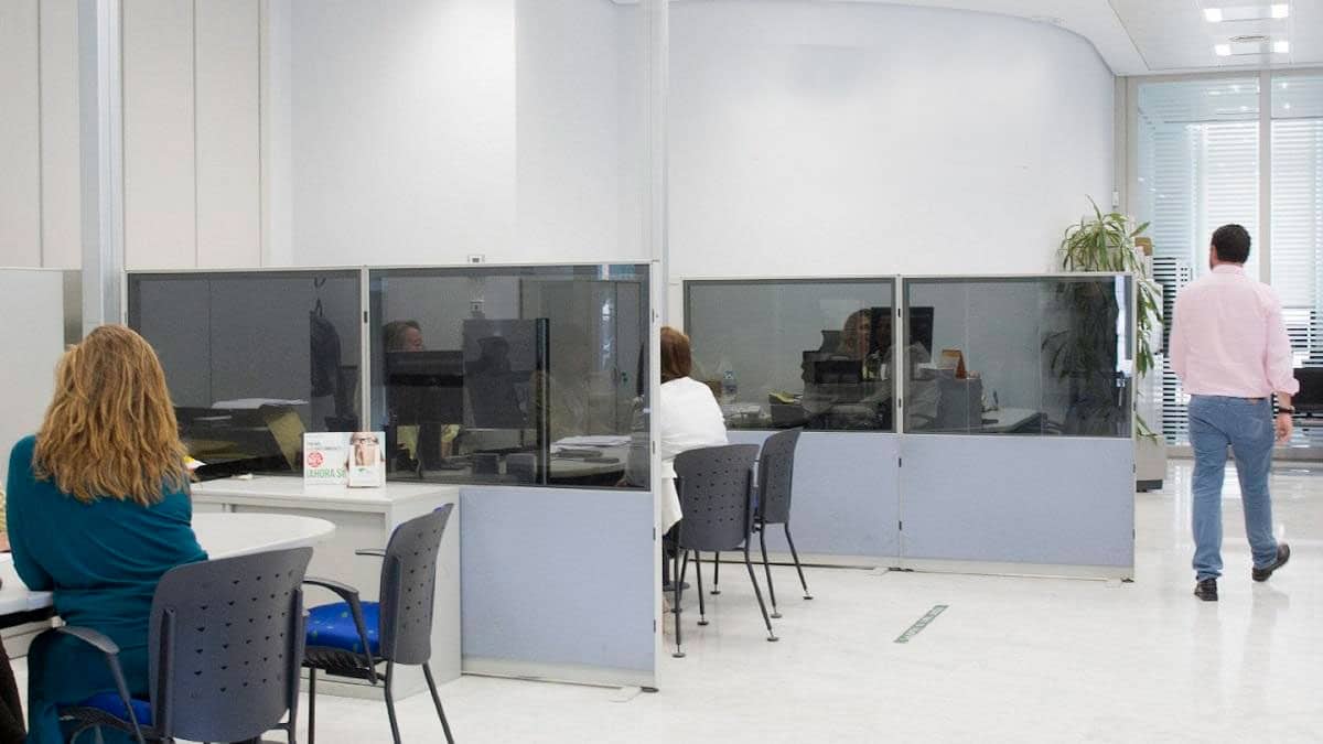 Persona realizando un trámite en una oficina bancaria para solicitar una cuenta gratuita sin comisiones