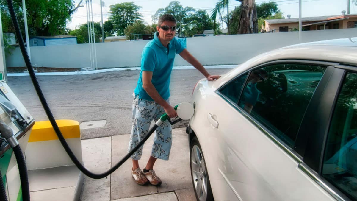 Hombre repostando gasolina en una gasolinera para evitar el error más común al llenar el depósito