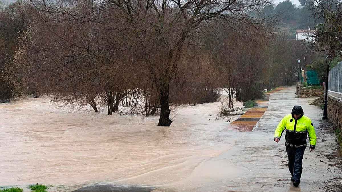 Un agente camina junto a un río desbordado tras las lluvias torrenciales provocadas por la borrasca Leonardo en Andalucía