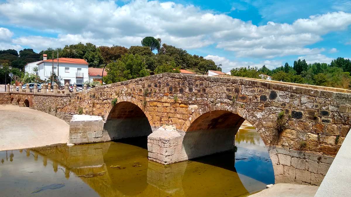 Puente de piedra sobre el río en un pueblo de la Sierra Morena de Sevilla incluido en el Pasaporte turístico