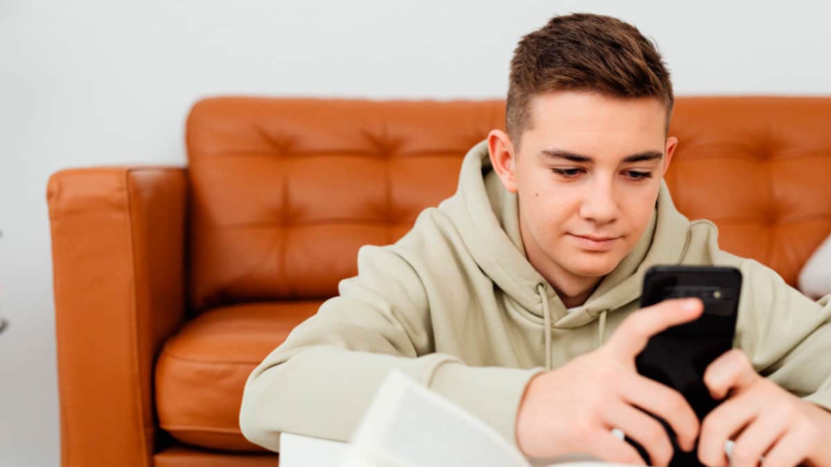 Joven consultando en su móvil cómo cobrar el Ingreso Mínimo Vital antes de los 23 años en 2026