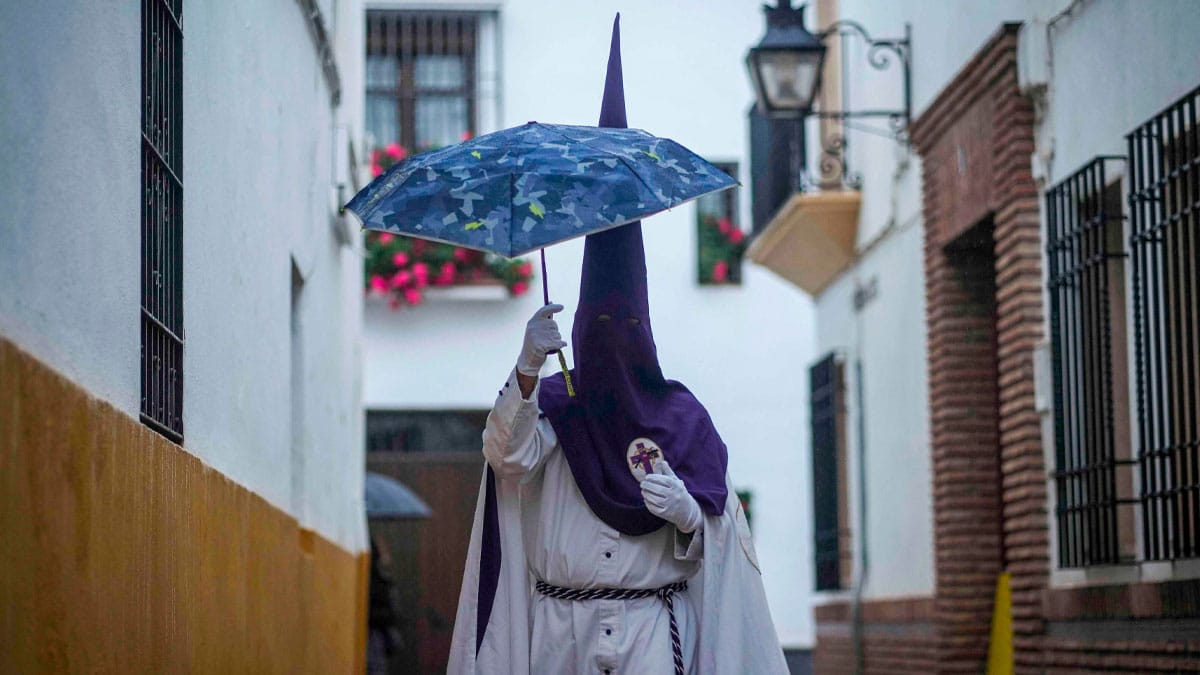 Nazareno con paraguas durante procesión de Semana Santa en Andalucía