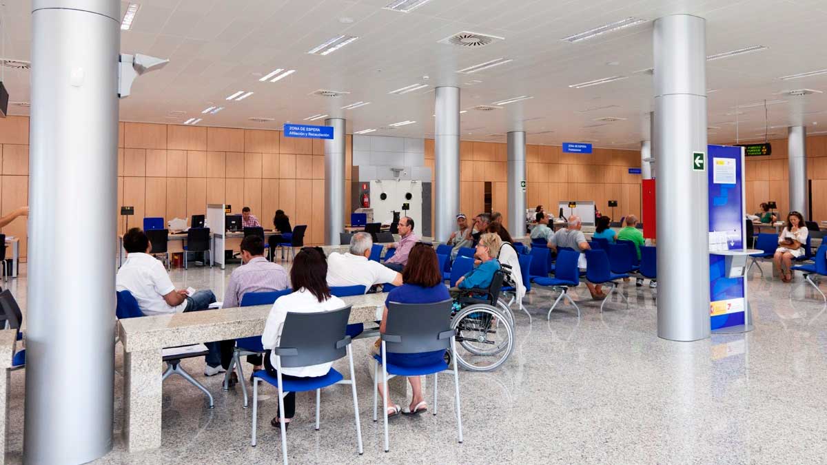 Personas esperando turno en una oficina de la Seguridad Social ante los retrasos en citas para jubilación y prestaciones del SEPE