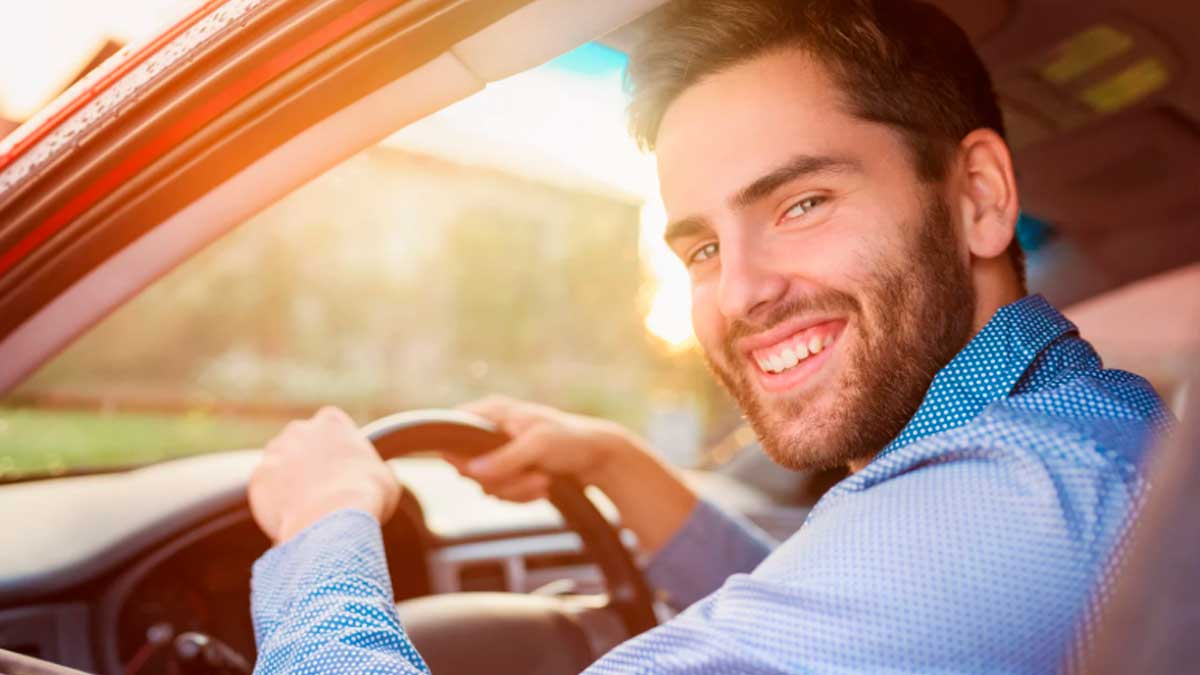 Conductor sonriendo al volante durante un viaje por carretera en Semana Santa ahorrando combustible