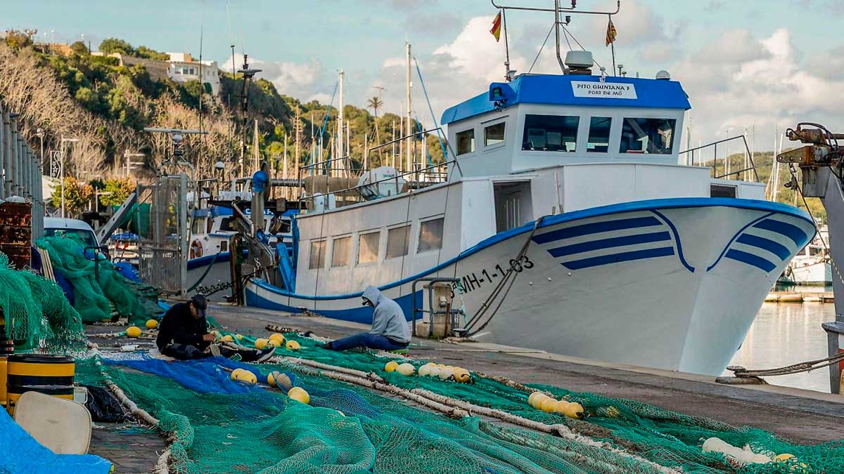 Barco pesquero en puerto andaluz con pescadores reparando redes tras temporales