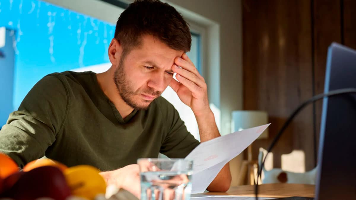 Hombre revisando la factura del agua en casa para solicitar el Bono Social Extraordinario