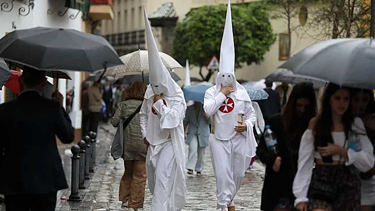 Nazarenos bajo la lluvia durante una procesión de Semana Santa en Andalucía por la borrasca Therese
