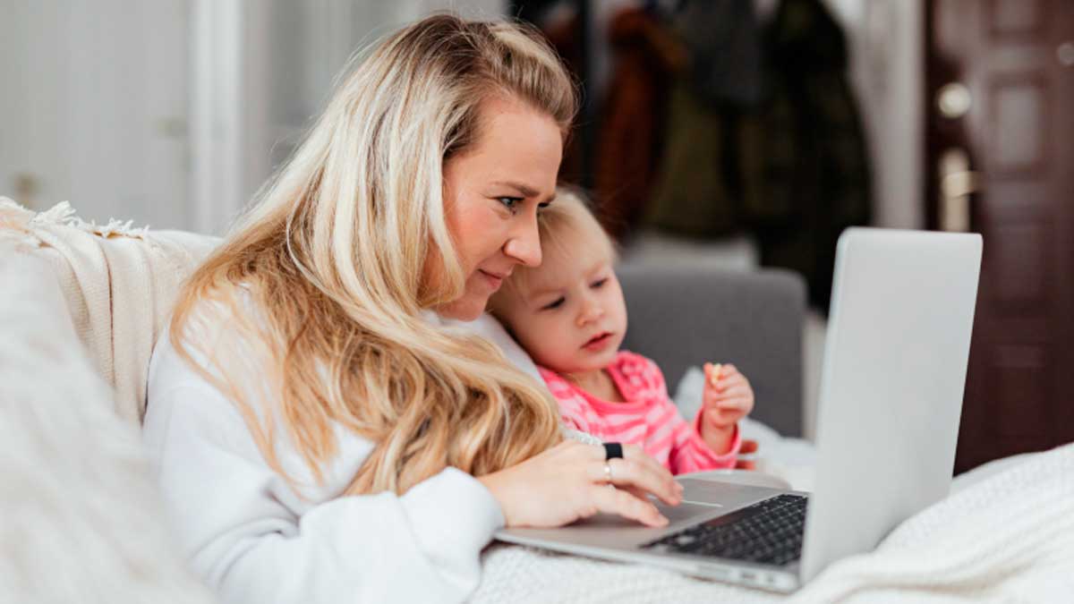 Mujer con su hija consultando el Ingreso Mínimo Vital desde casa, prestación donde el 68% de titulares son mujeres