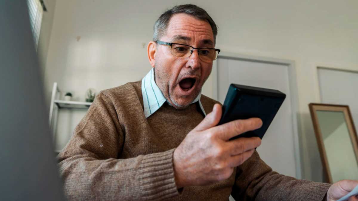 Trabajador sorprendido mirando el móvil tras conocer los requisitos de la jubilación anticipada forzosa en 2026