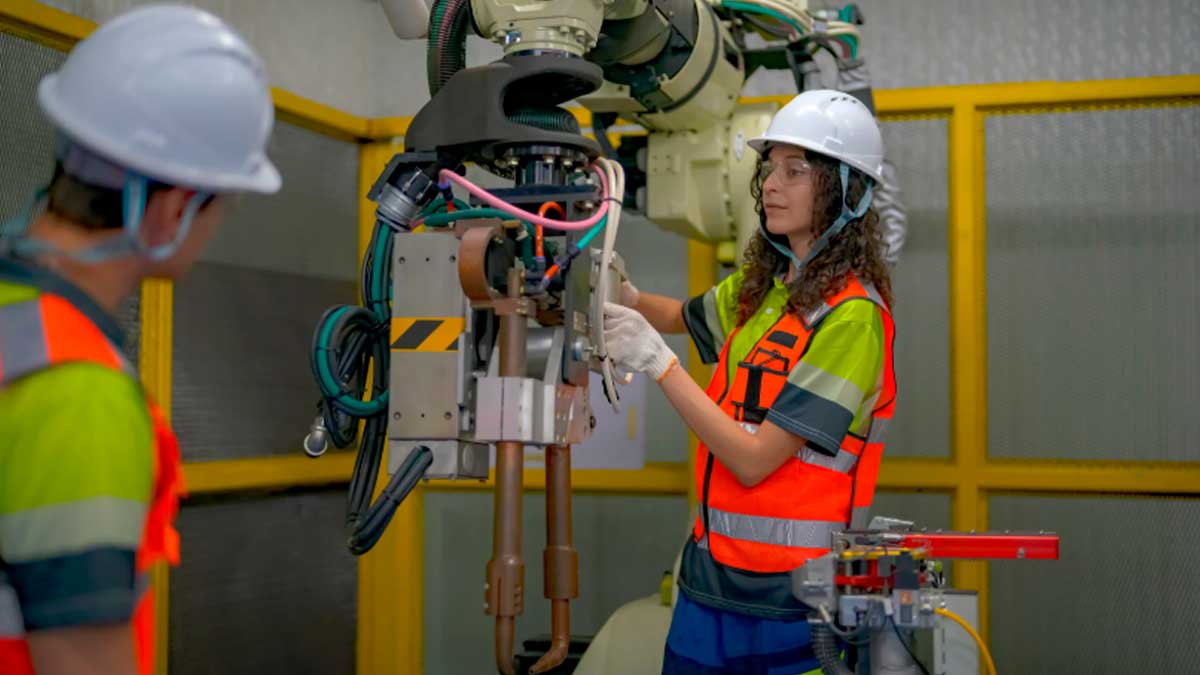 Trabajadora con casco y chaleco de seguridad operando maquinaria industrial en una fábrica
