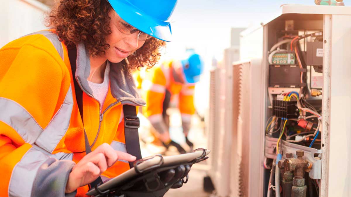 Técnica revisando instalación eléctrica industrial con tablet