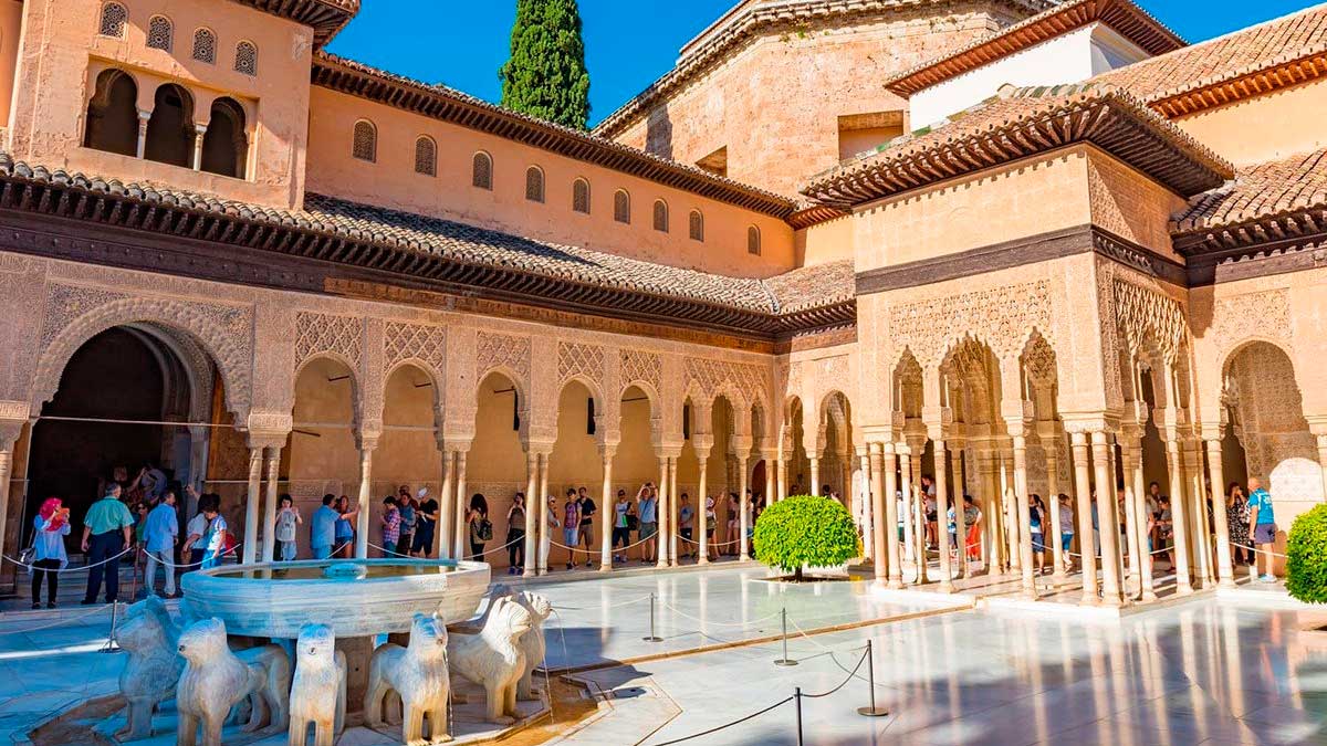 Patio de los Leones en la Alhambra de Granada con turistas visitando el monumento histórico