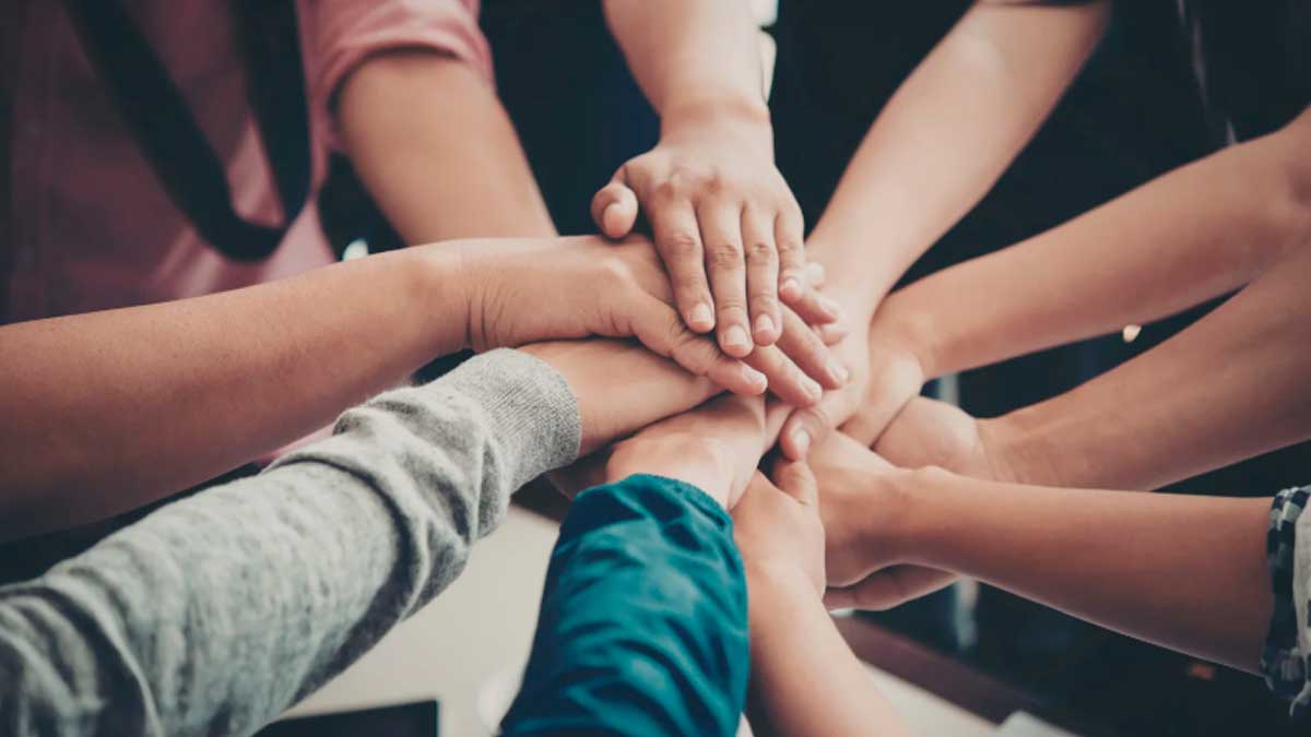 Personas uniendo manos en apoyo a andaluces en el extranjero con ayudas del BOJA