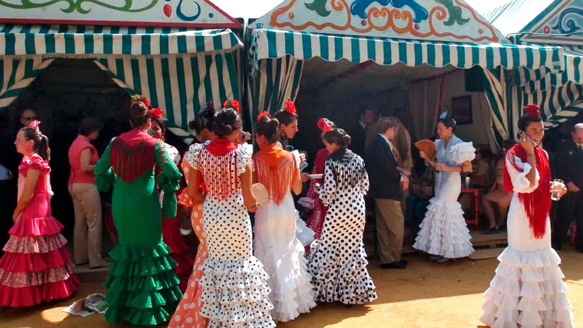 Personas con trajes de flamenca en casetas de la Feria de Abril de Sevilla