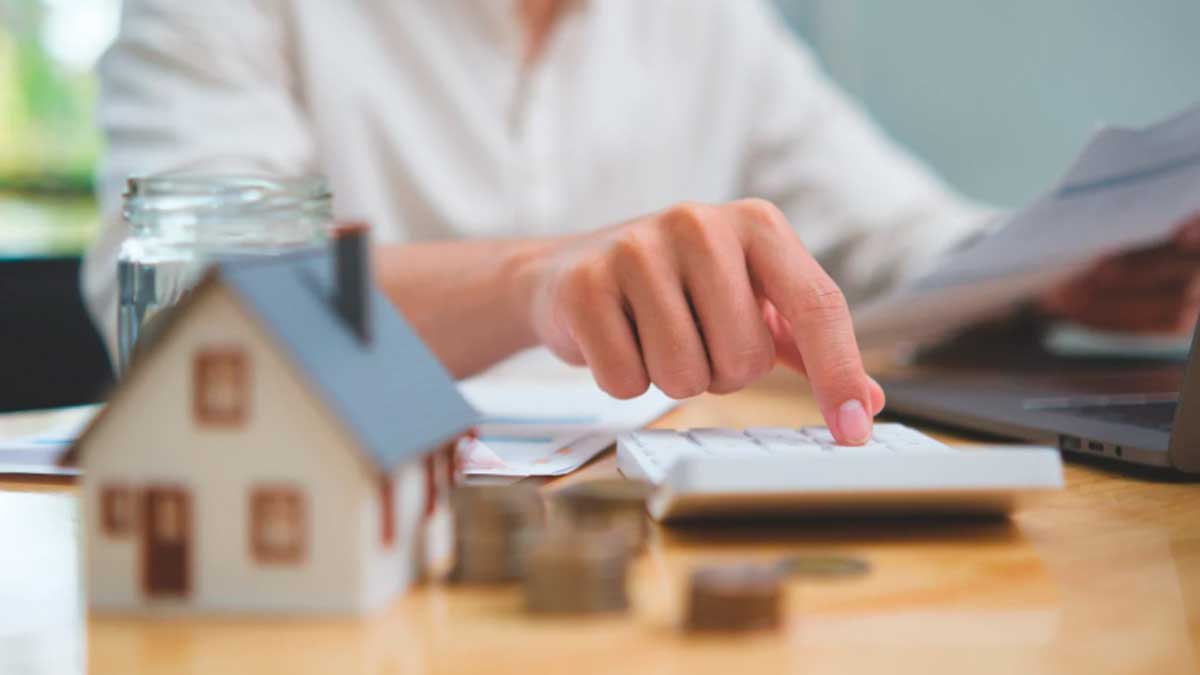 Persona calculando gastos de alquiler con casa en maqueta y documentos de la Renta