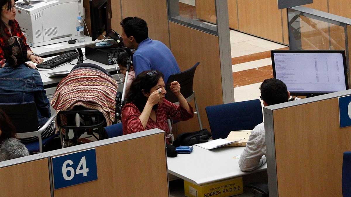 Contribuyentes realizando la declaración de la renta en oficina de la Agencia Tributaria en España