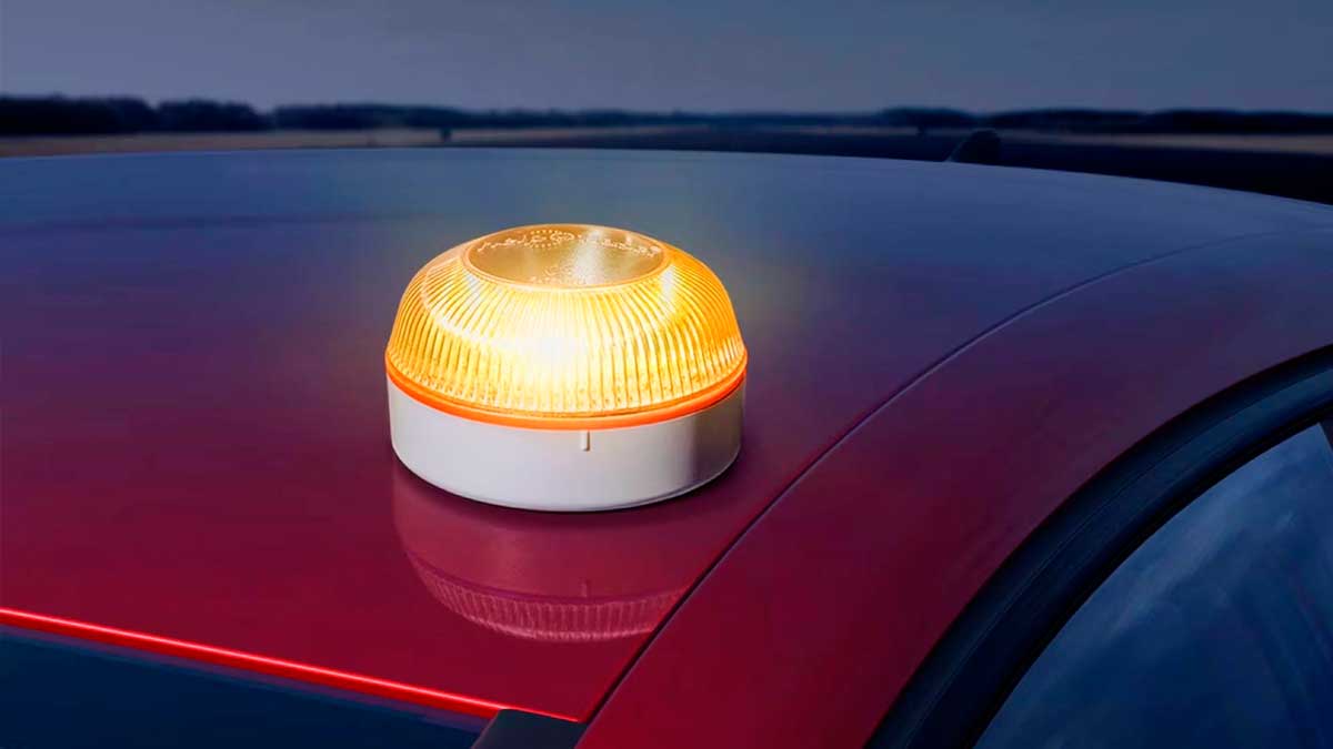 Baliza V16 encendida sobre el techo de un coche en carretera como dispositivo de preseñalización de la DGT