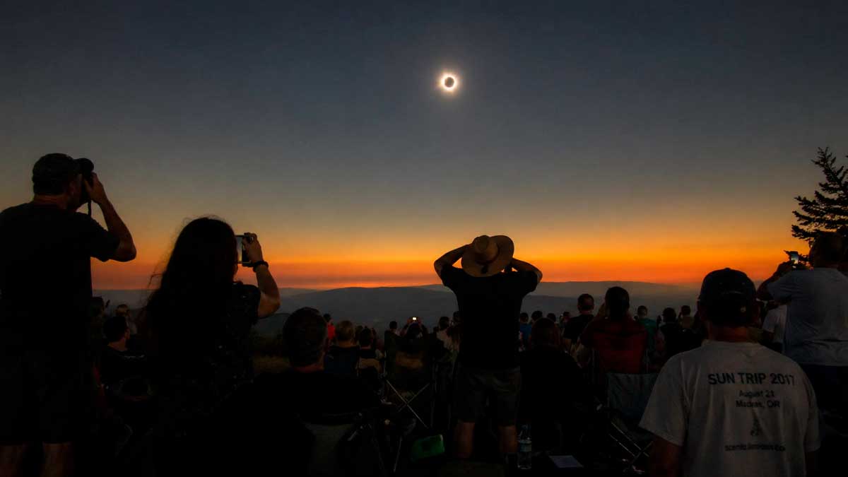 Grupo de personas observando un eclipse solar al atardecer desde un mirador en España