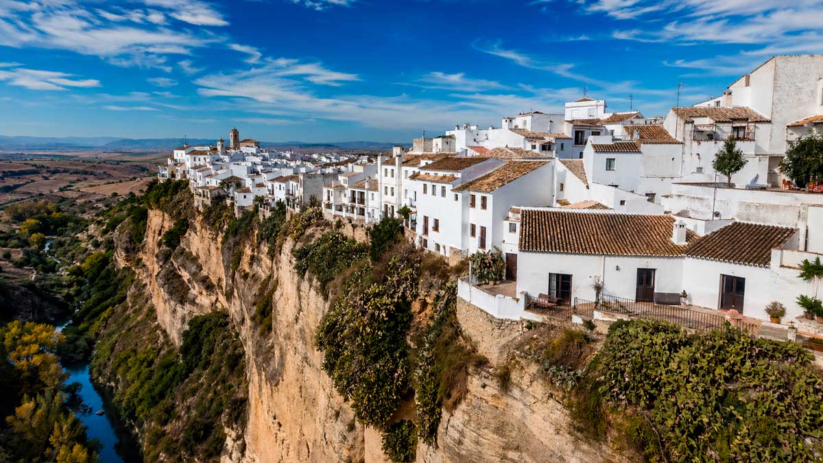 Pueblos blancos de Cádiz sobre acantilado con casas encaladas y vistas al río