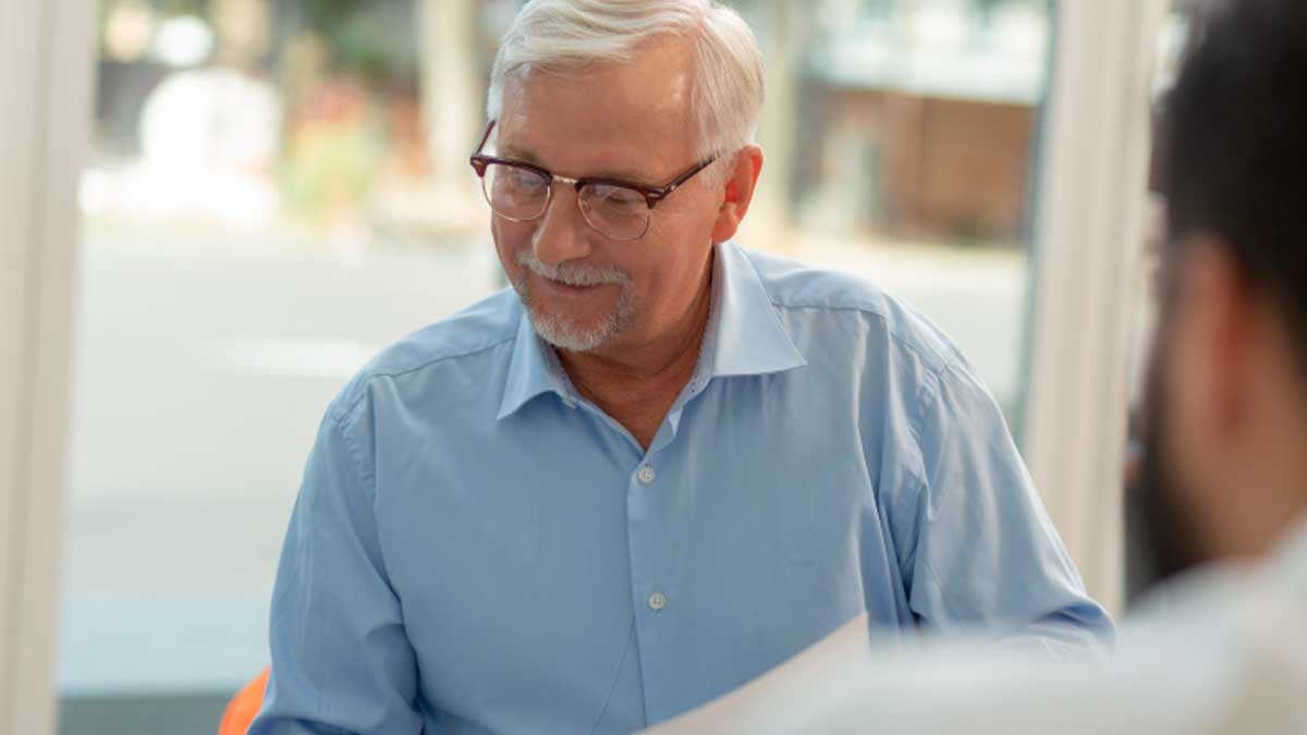 Hombre mayor revisando documentos sobre jubilación en oficina