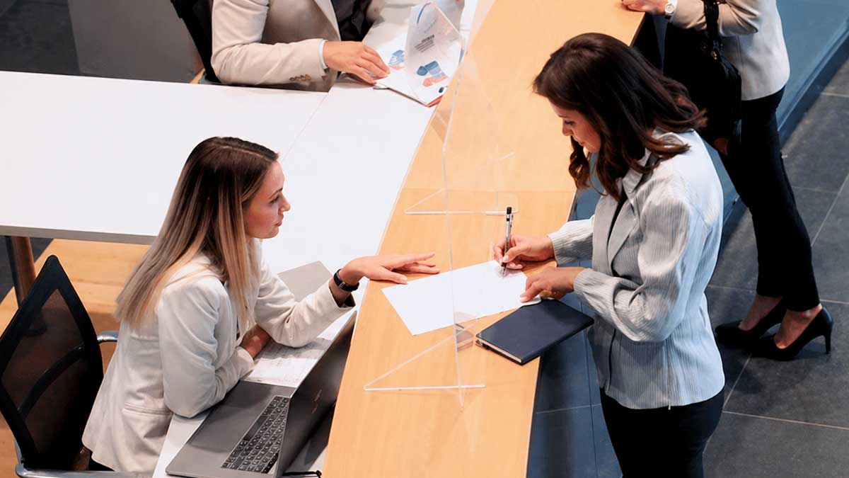 Persona firmando documentos para cerrar una cuenta corriente en una oficina bancaria moderna