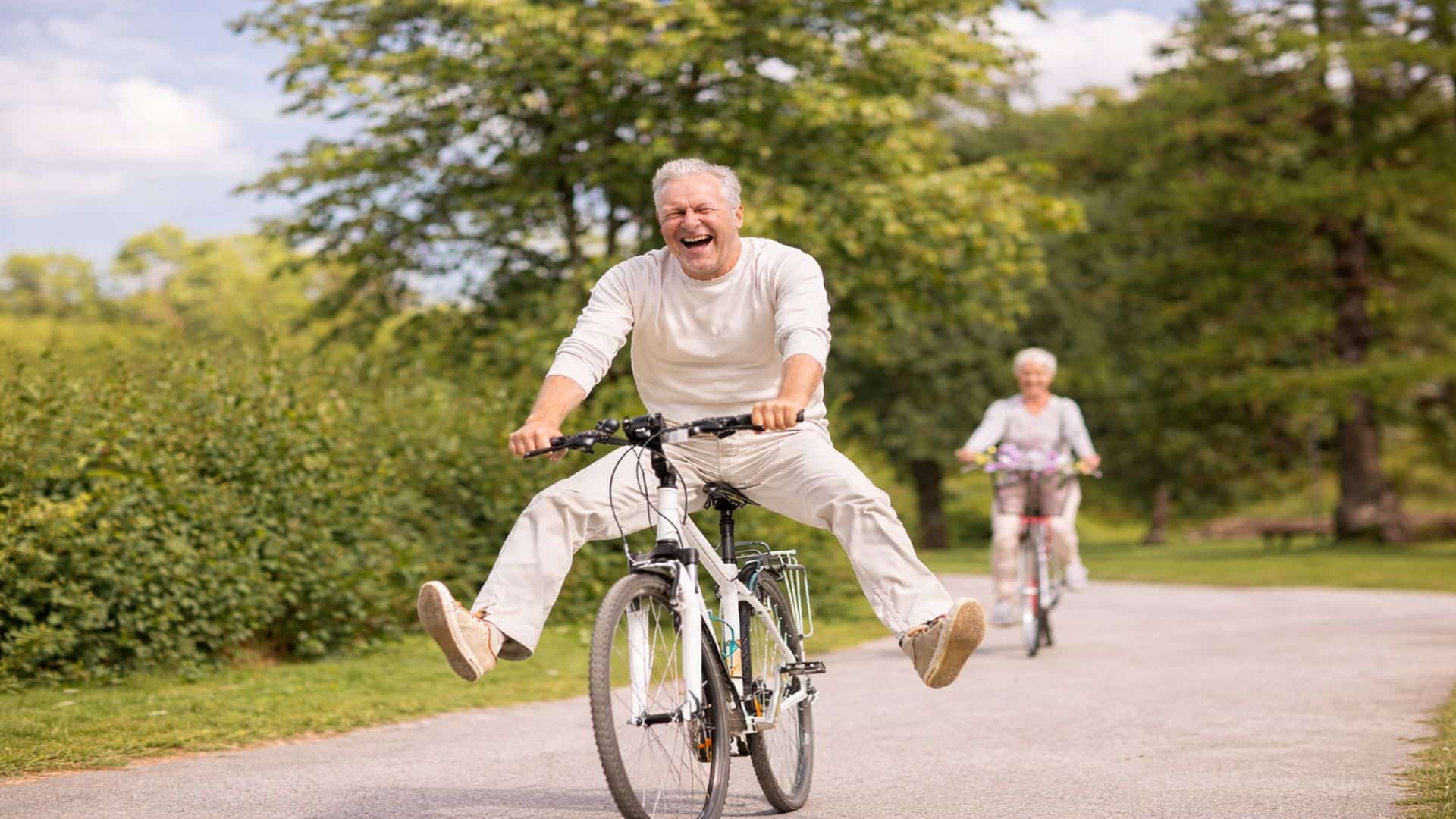 Personas mayores disfrutando de la jubilación y felicidad montando en bicicleta en un parque