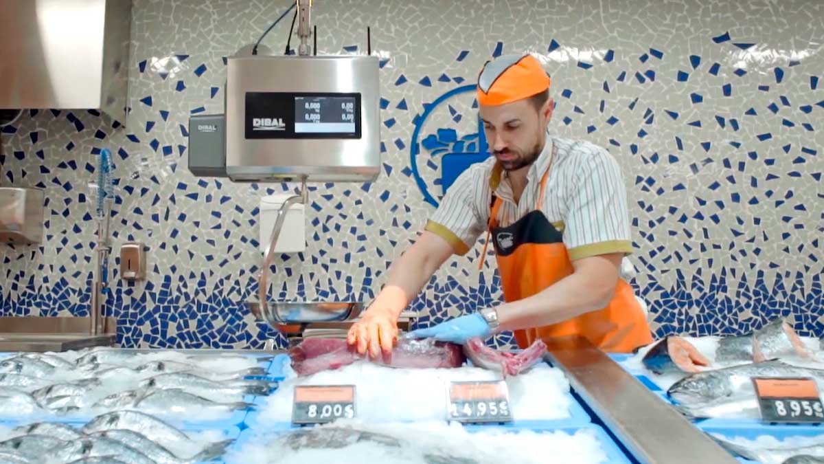 Trabajador de Mercadona en pescadería preparando pescado durante campaña de verano en Andalucía
