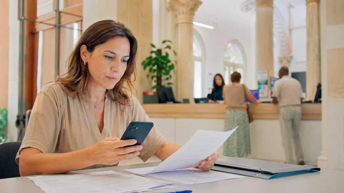 Mujer revisa documentos y usa el móvil para reclamar a la Administración en Andalucía