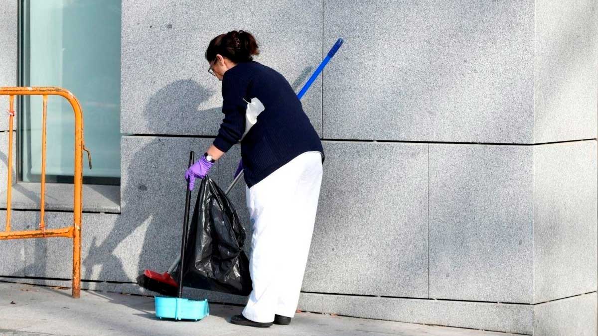 Trabajadora de limpieza recogiendo basura en edificio, empleo del SAE en Andalucía con incorporación inmediata