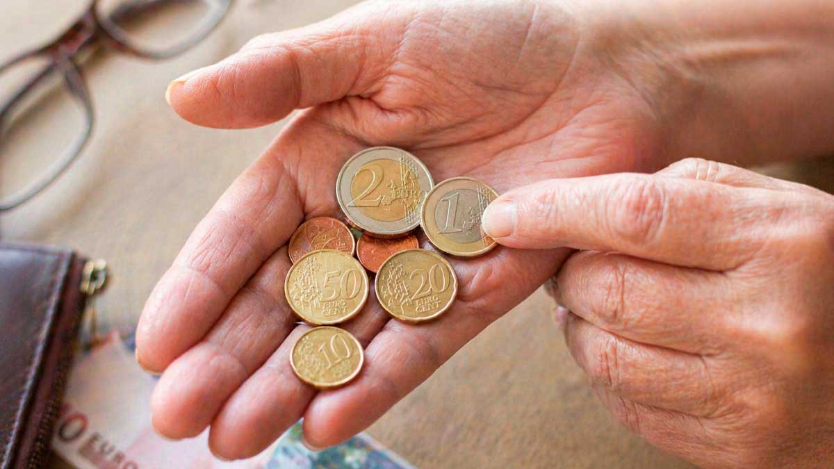 Persona mayor contando monedas en euros para revisar ingresos de pensión