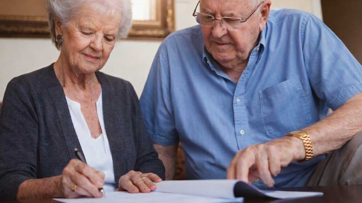 Pareja mayor revisando documentos de vivienda para la declaración de la Renta tras mudarse a una residencia