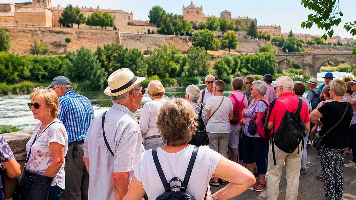 Grupo de jubilados en un viaje del IMSERSO junto a un río durante una excursión turística en España