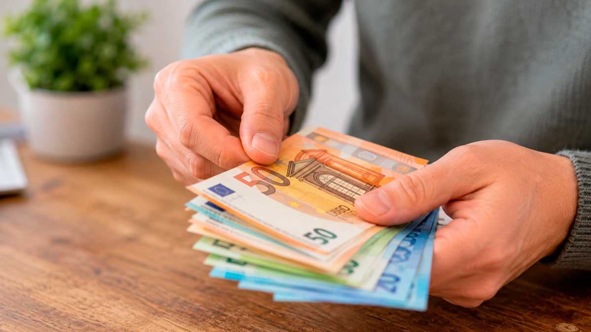 Desempleado contando billetes de euro tras acceder a una ayuda del SEPE en Andalucía